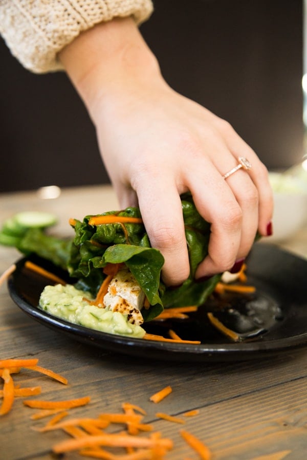 Tofu wrap being grabbed by hand and dipped into tzatziki sauce