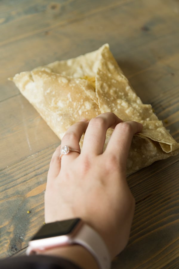 Folding one of our curry tofu wraps on a wood board