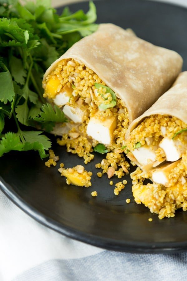A wrap with tofu and quinoa on a black plate