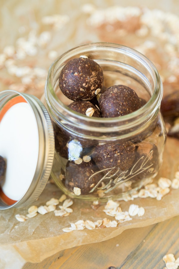 Chocolate energy balls in a mason jar with oats scattered around it