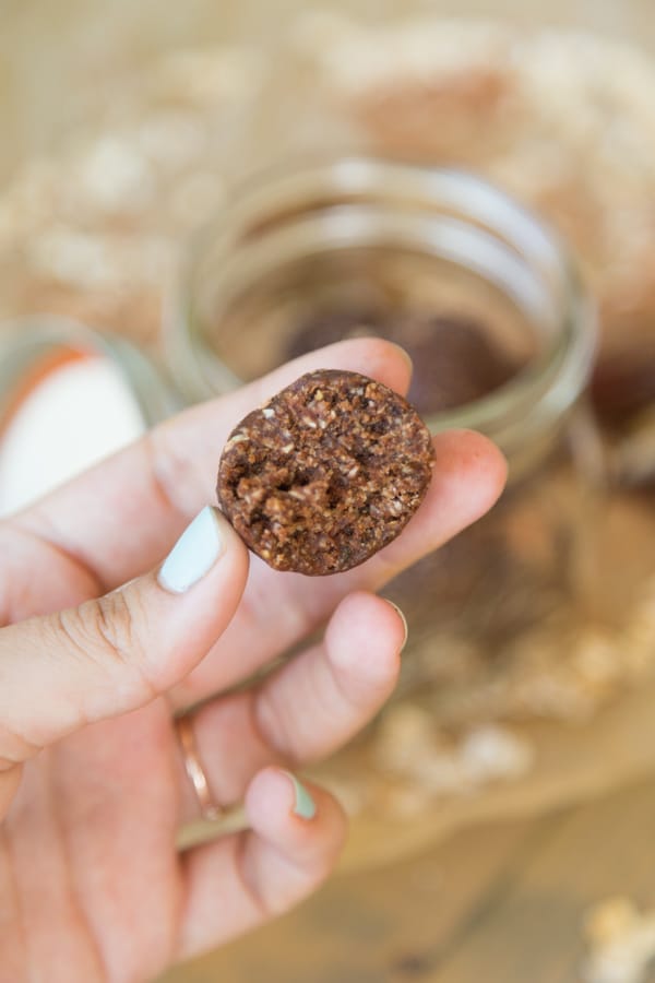 A hand holding a chocolate energy ball with a bite out of it