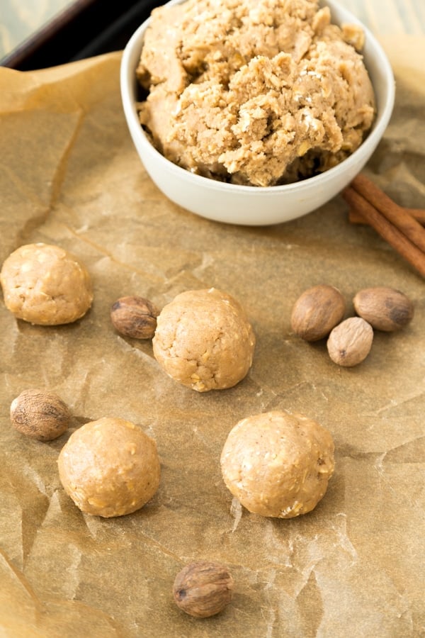 apple oat cookie dough on parchment paper with cinnamon sticks and whole nutmeg