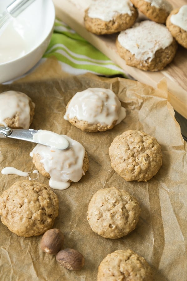 Apple oat cookies being frosted with a butter knife on parchment paper