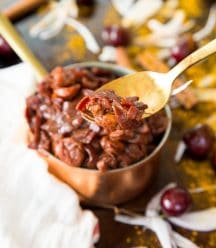 Cherry Onion confit on a gold spoon in front of a copper pot