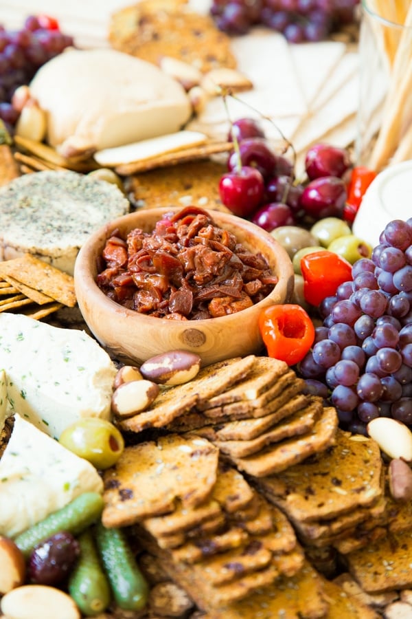 Cherry Confit on a cheese platter with vegan nut cheeses, grapes, peppers, olives, and a variety of crackers