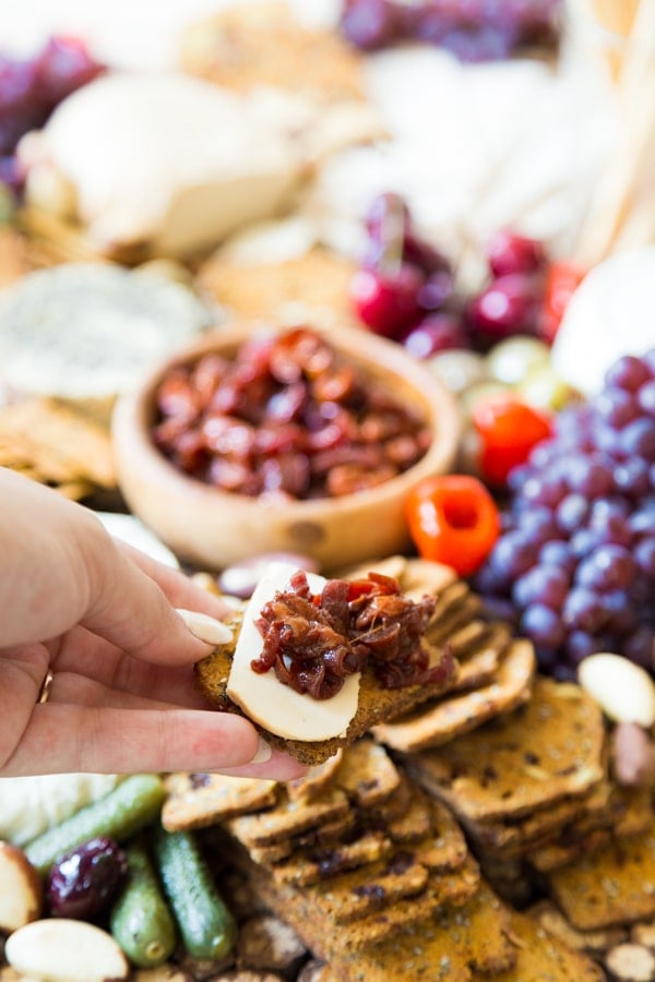 Cherry confit cracker with smoked mozzarella in front of a vegan cheese plate