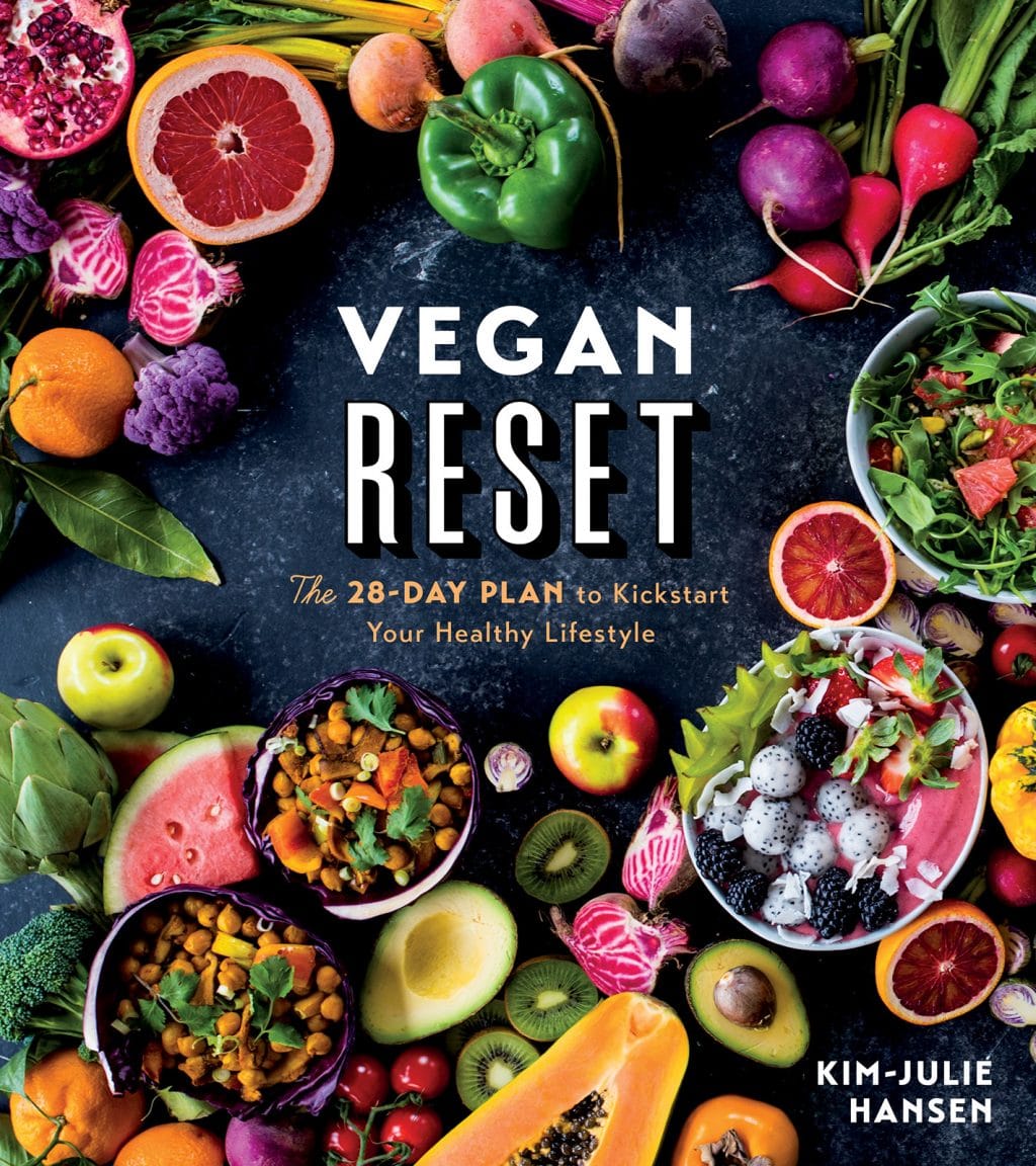 The cover of the cookbook, Vegan Reset. A dark background with vibrant fruit and bowls of vegan food