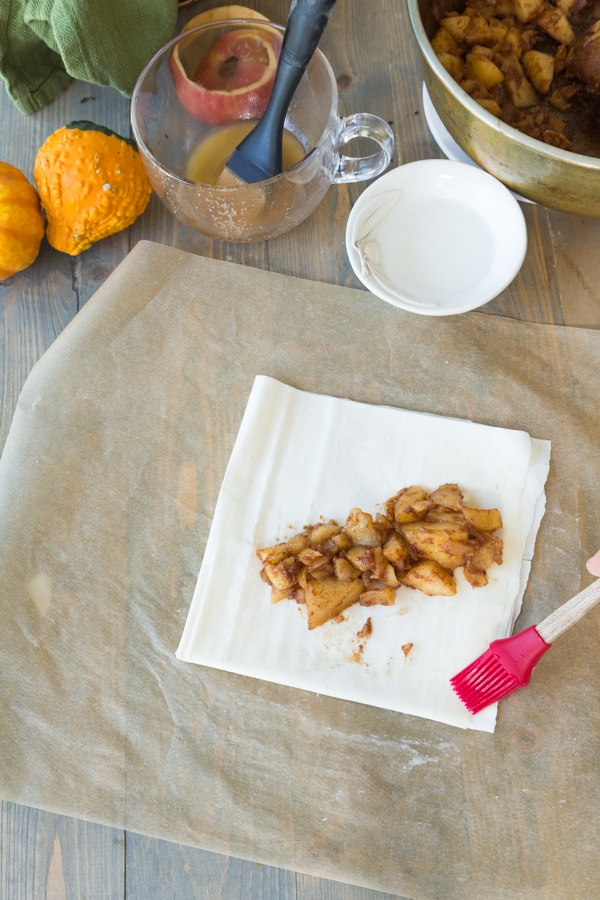 A square of phyllo dough with apple spice filling in the center to make apple turnovers