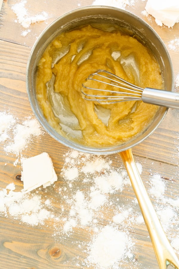 Butter and flour cooking in a copper pan to make a vegan roux with flour and butter pieces on a wood board