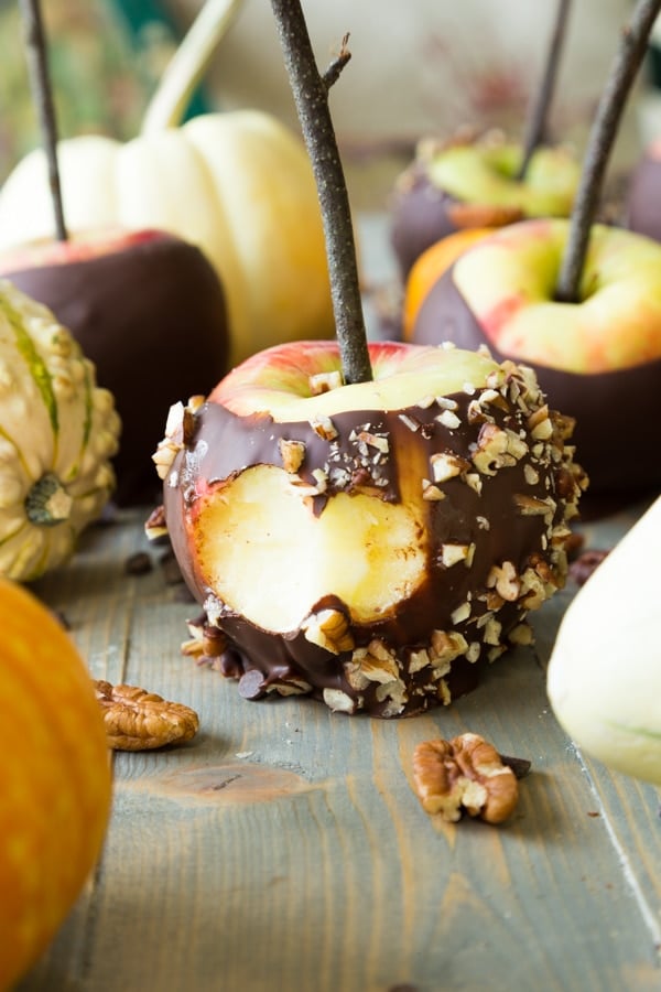 Chocolate covered apples with nuts and a bite taken out of the apple in the front