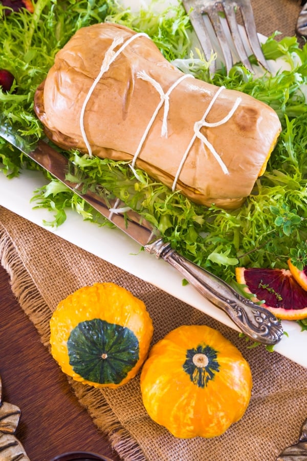 Tied up stuffed Butternut squash on a bed of greens with blood oranges and pumpkins