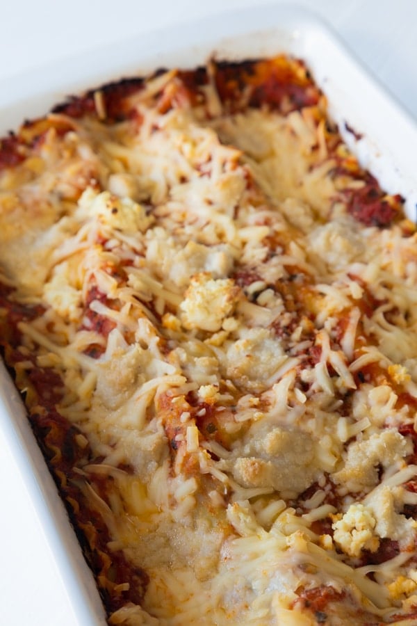 A pan of baked vegan spinach lasagna in a white ceramic pan