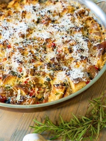 A vegan breakfast casserole in a round copper pan with herbs and garlic next to it