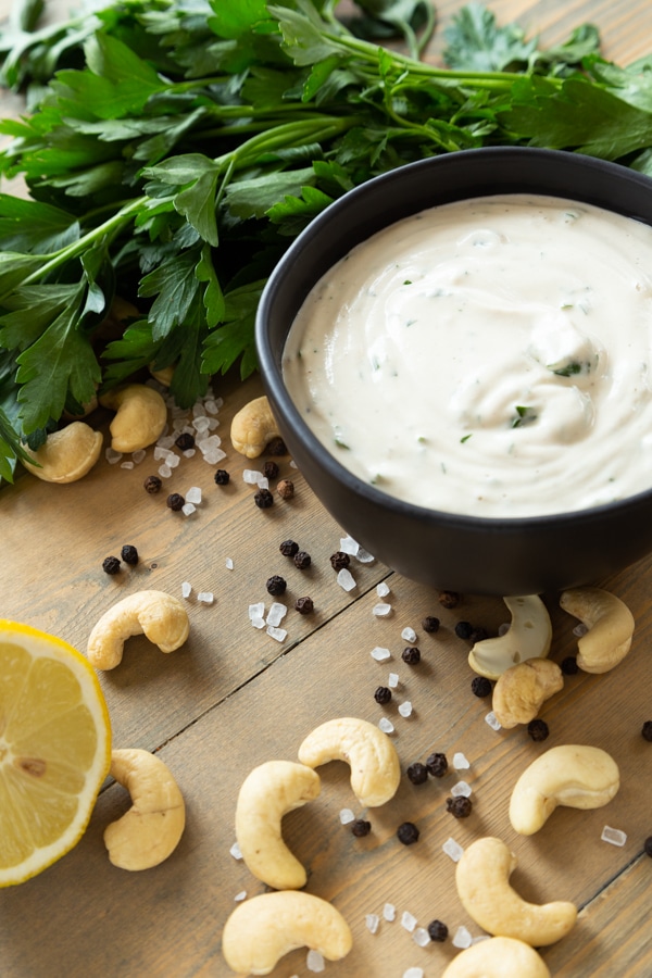 Twice Baked Ranch potatoes ranch sauce on a wood board with cashews, lemon, salt and pepper, with parsley