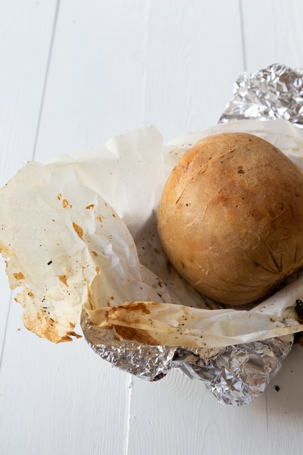 A roasted Tofurky Veggie Roast on a piece of foil and white parchment paper