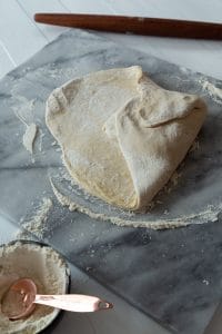 croissant dough being folded into an envelope on a marble board on the second fold