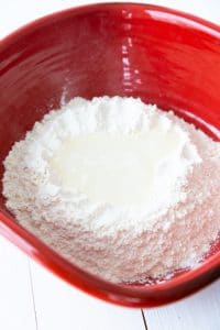 A red bowl with flour and a well in the center filled with water and salt.