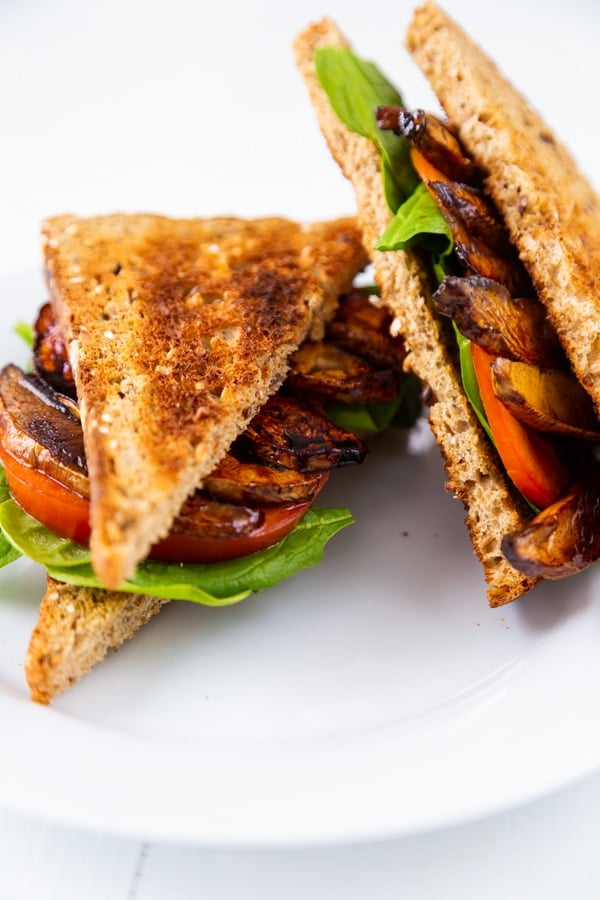 A PLT sandwich cut in half on a white plate