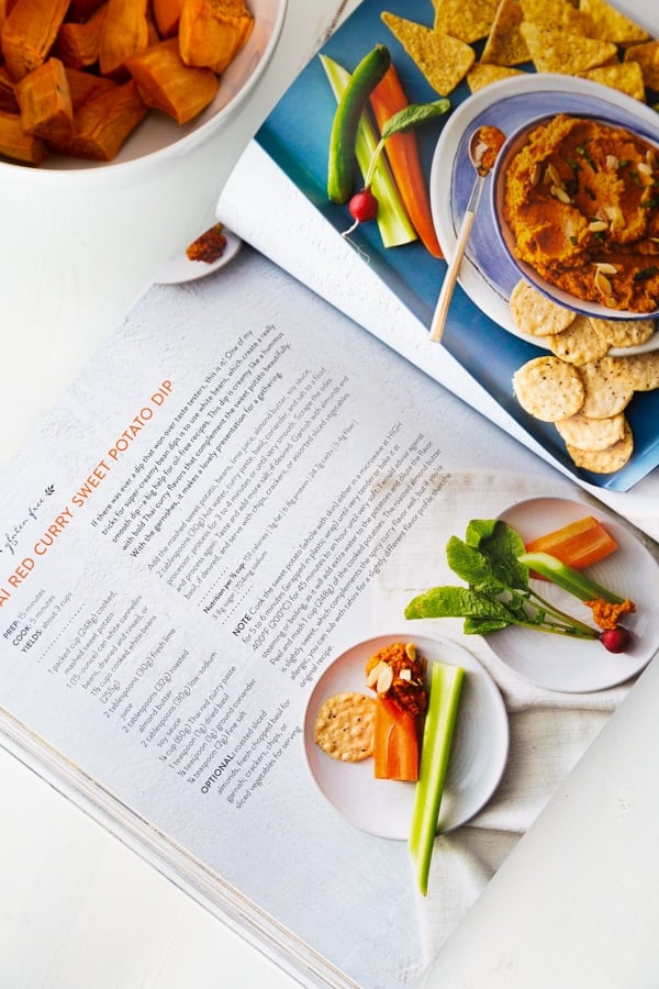 The Vegan 8 cookbook opened to the Thai Curry Dip page with a bowl of the dip in the background