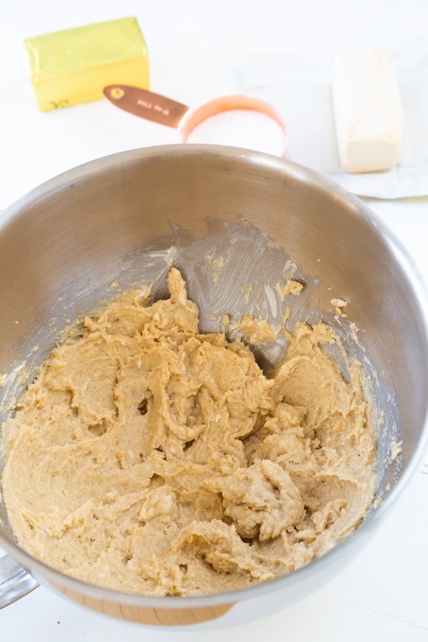 Beaten butter and sugar in a silver mixing bowl for chocolate chip cookies.