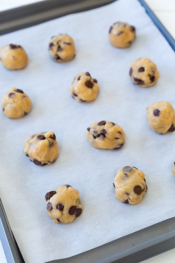 Chocolate chip cookies on a baking sheet with parchment paper ready to be baked. 
