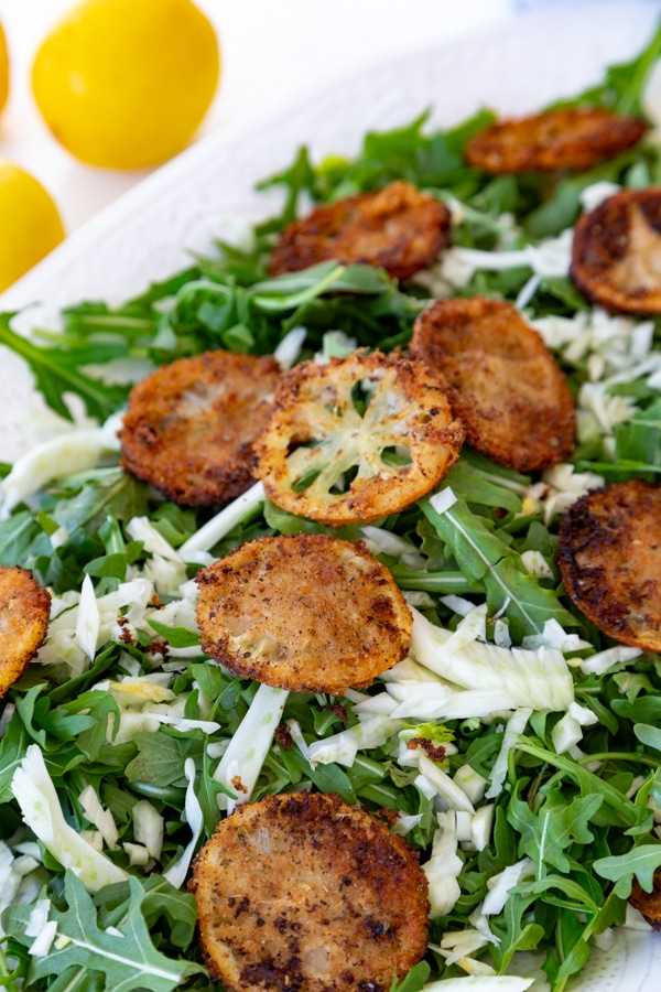 An arugula and fennel salad with fried lemons and a creamy dressing with lemons in the background