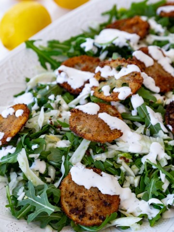 A salad with fried lemons and a creamy dressing.