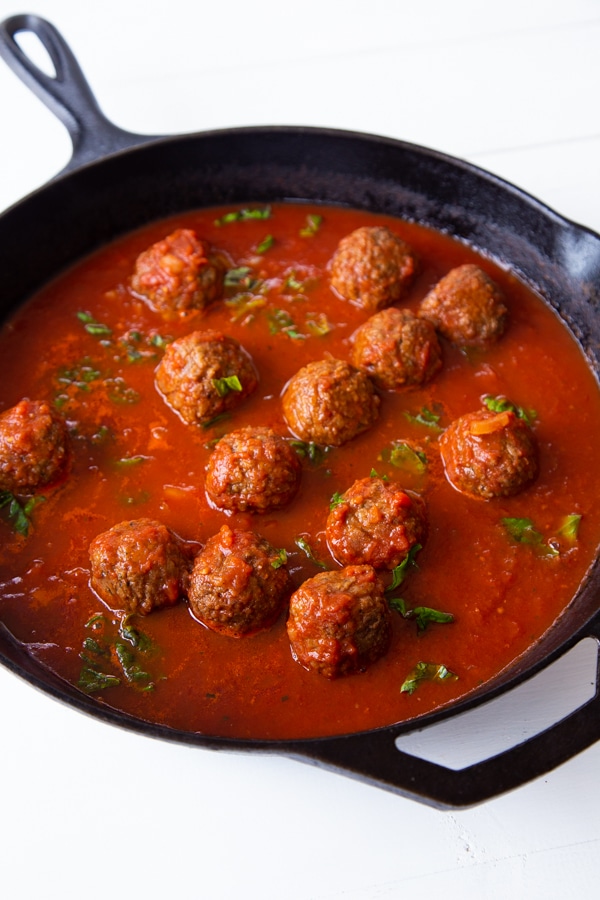 Meatballs in red sauce in an iron skillet for our vegan meatball sub