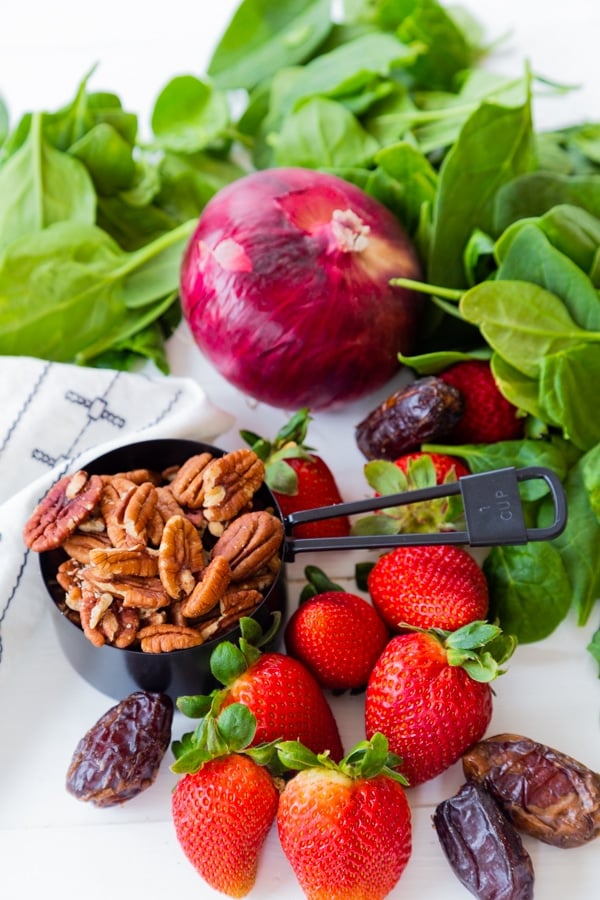 Spinach, strawberries, pecans, dates, and a red onion for salad