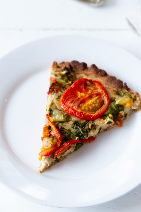 A slice of tomato tart on a white plate