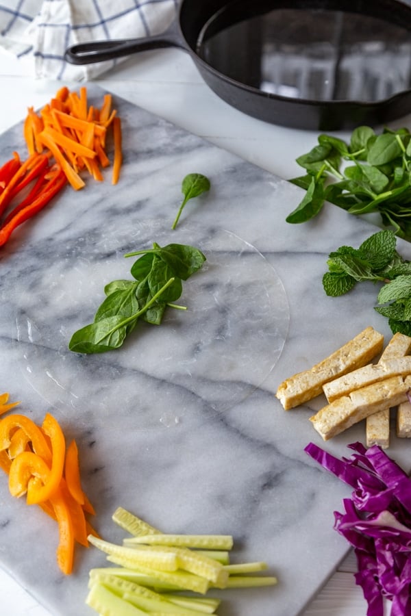 Rice paper with herbs on top on a marble board.