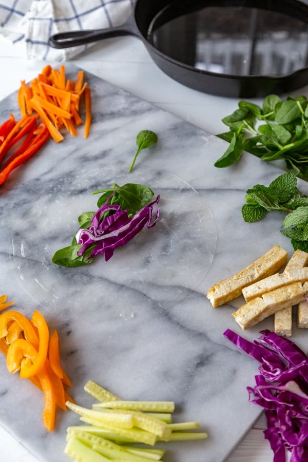 Rice paper with red cabbage and greens on a marble board.