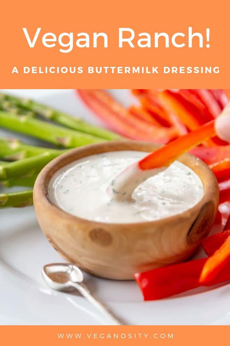A Pinterest pin with orange background for vegan ranch dressing with a picture of a wood bowl of ranch and a hand dipping a slice of bell pepper in the dip.