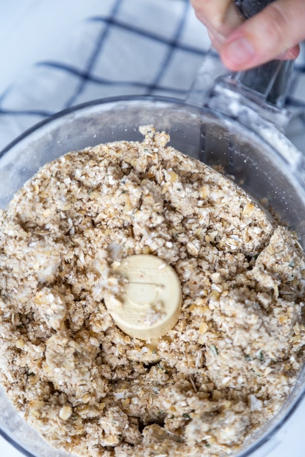 A food processor with crumbled flour and oats.