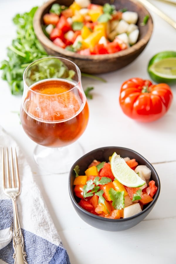 A white wood table with bowls of salad and a glass of beer.