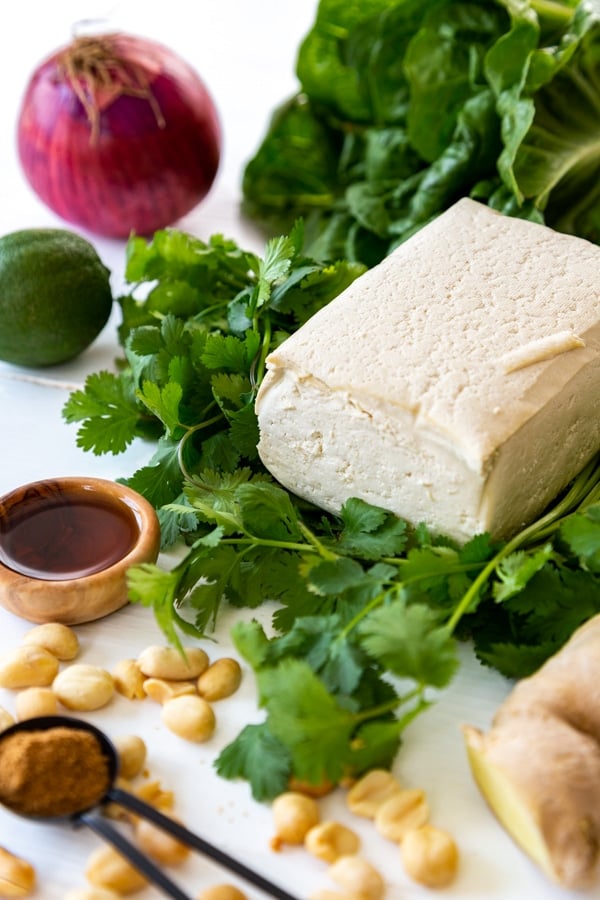 Ingredients for lettuce wraps, a block of tofu, lettuce, peanuts, herbs and spices. 