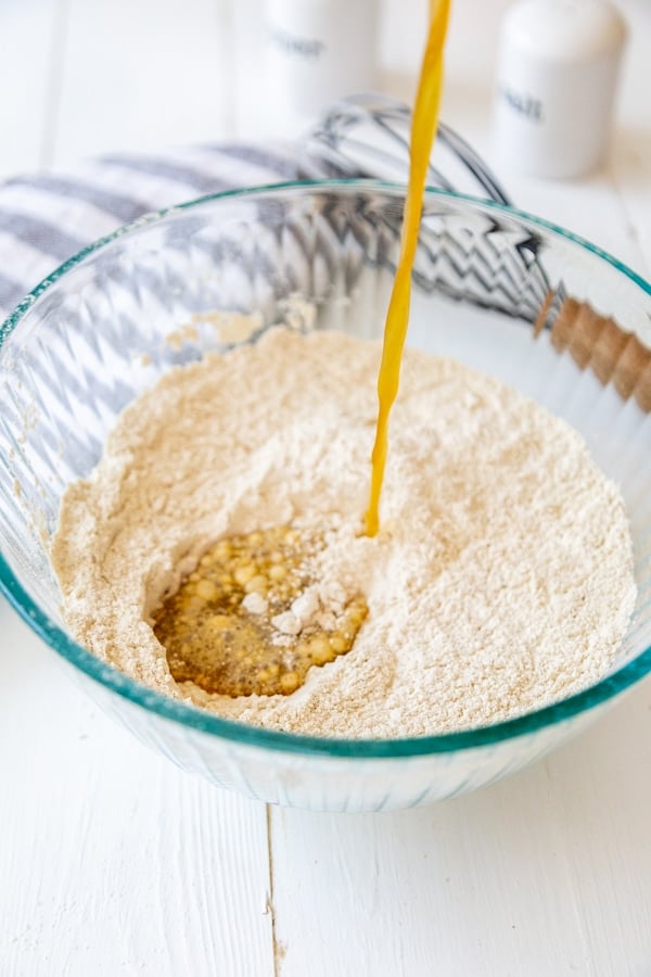 Brown liquid being poured into a bowl of dry flour.