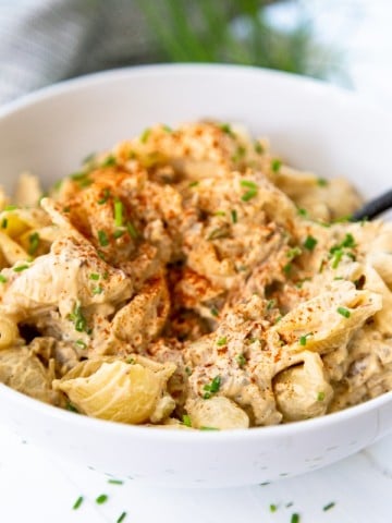 A white bowl with buffalo chicken mac and cheese with a fork in the bowl.