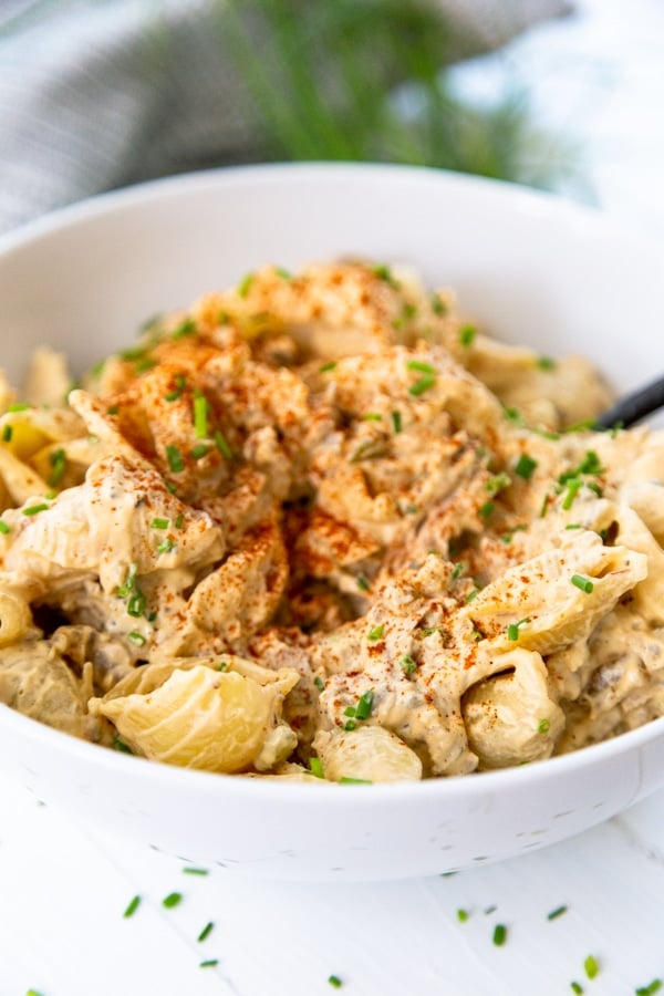 A white bowl with buffalo chicken mac and cheese with a fork in the bowl. 