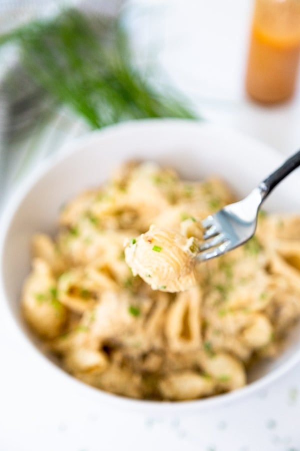 A fork with buffalo chicken mac and cheese over a bowl of the food. 