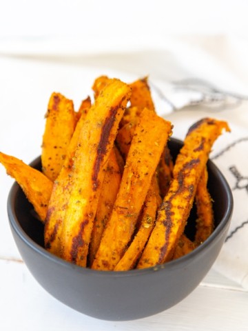 A black bowl filled with sweet potato fries.
