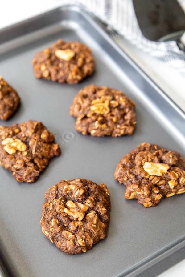 Chocolate cookies with walnuts on a baking sheet.