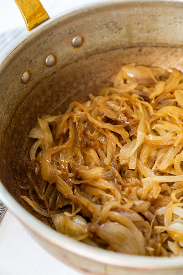 A copper pan with caramelized onions and broth.