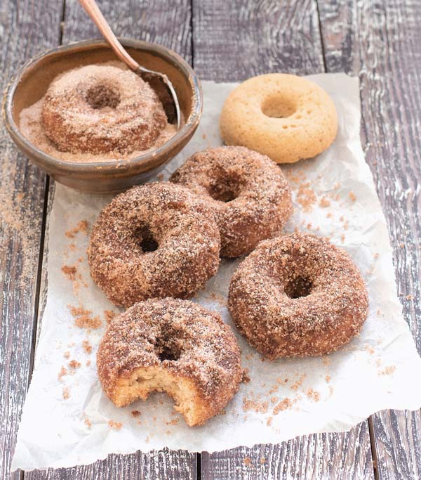 A pile of sugar doughnuts on parchment paper.