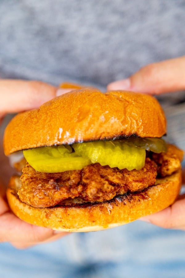 A person holding a fried chicken sandwich.