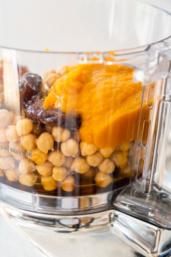 A food processor with chickpeas, pumpkin puree, dates and spices.