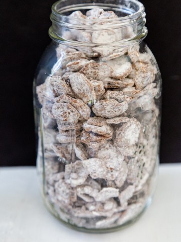 A clear mason jar filled with puppy chow snacks.