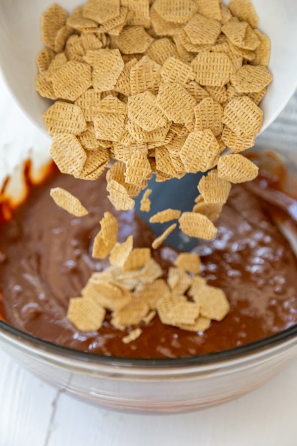 Rice cereal being poured into a bowl of melted chocolate.