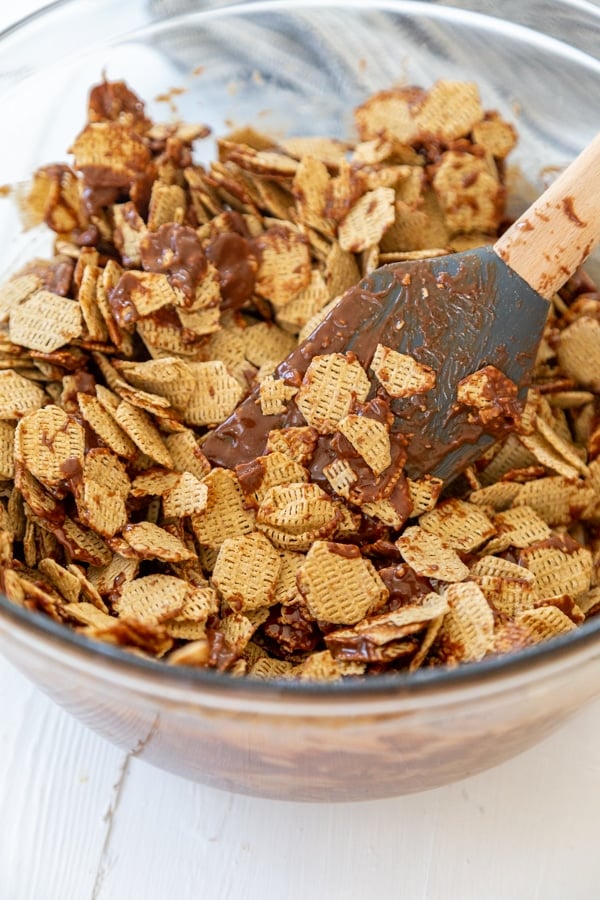 A wooden spoon stirring rice cereal into melted chocolate.