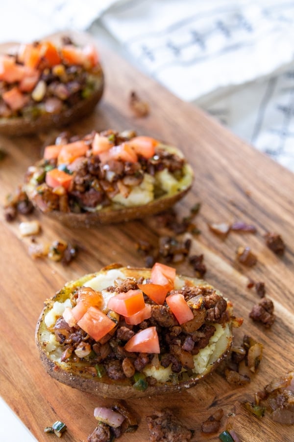 Potato skins filled with taco filling and topped with tomato.